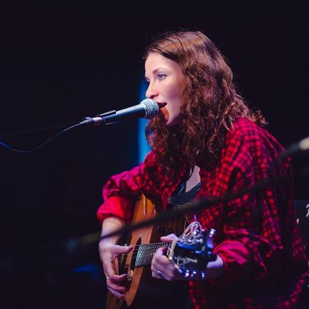 Rosie Doonan singing at microphone and playing guitar