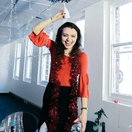 Jackie Edwards smiling with a glass raised above her head