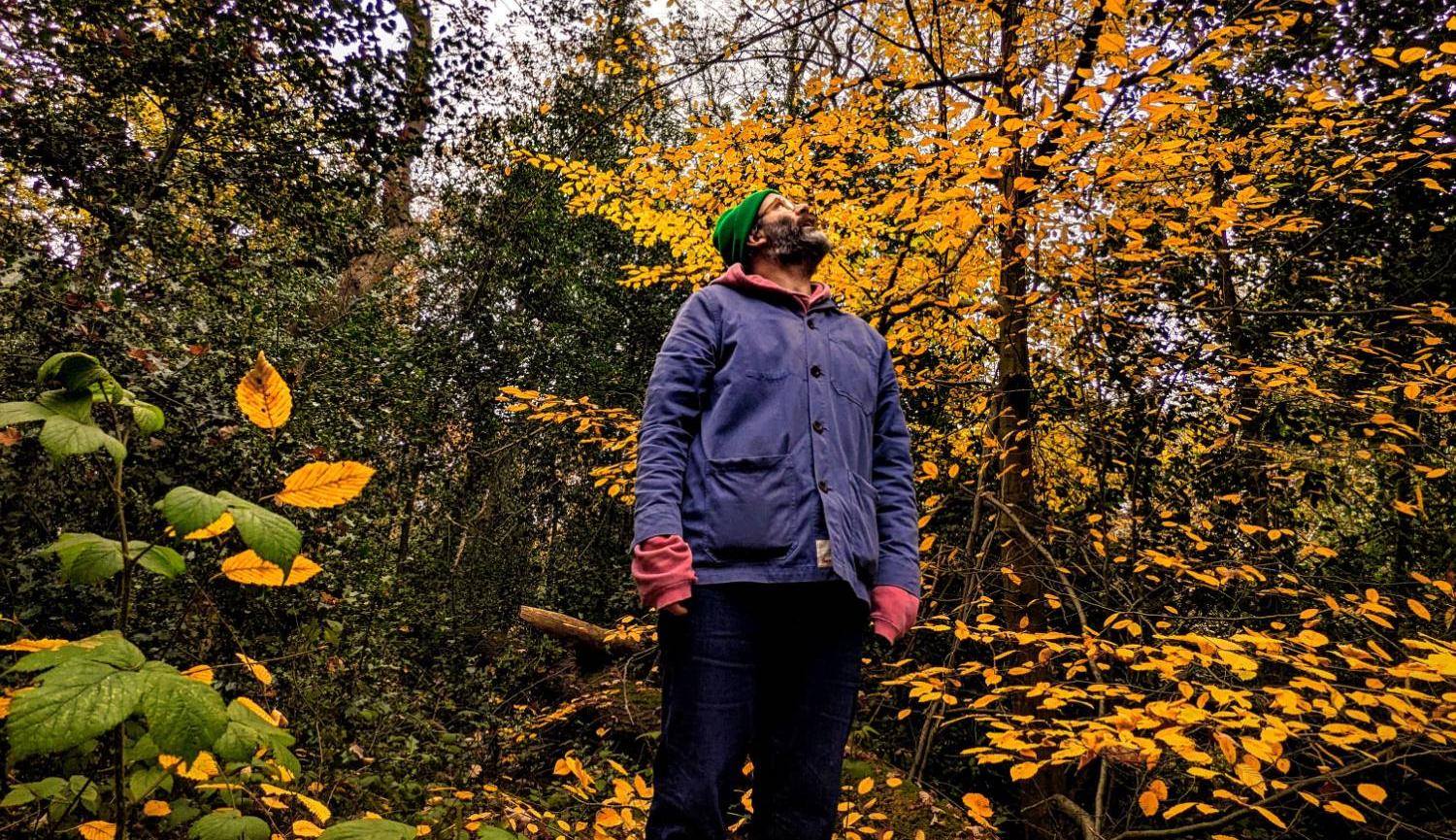 Daniel Kitson in a wood looking to the sky