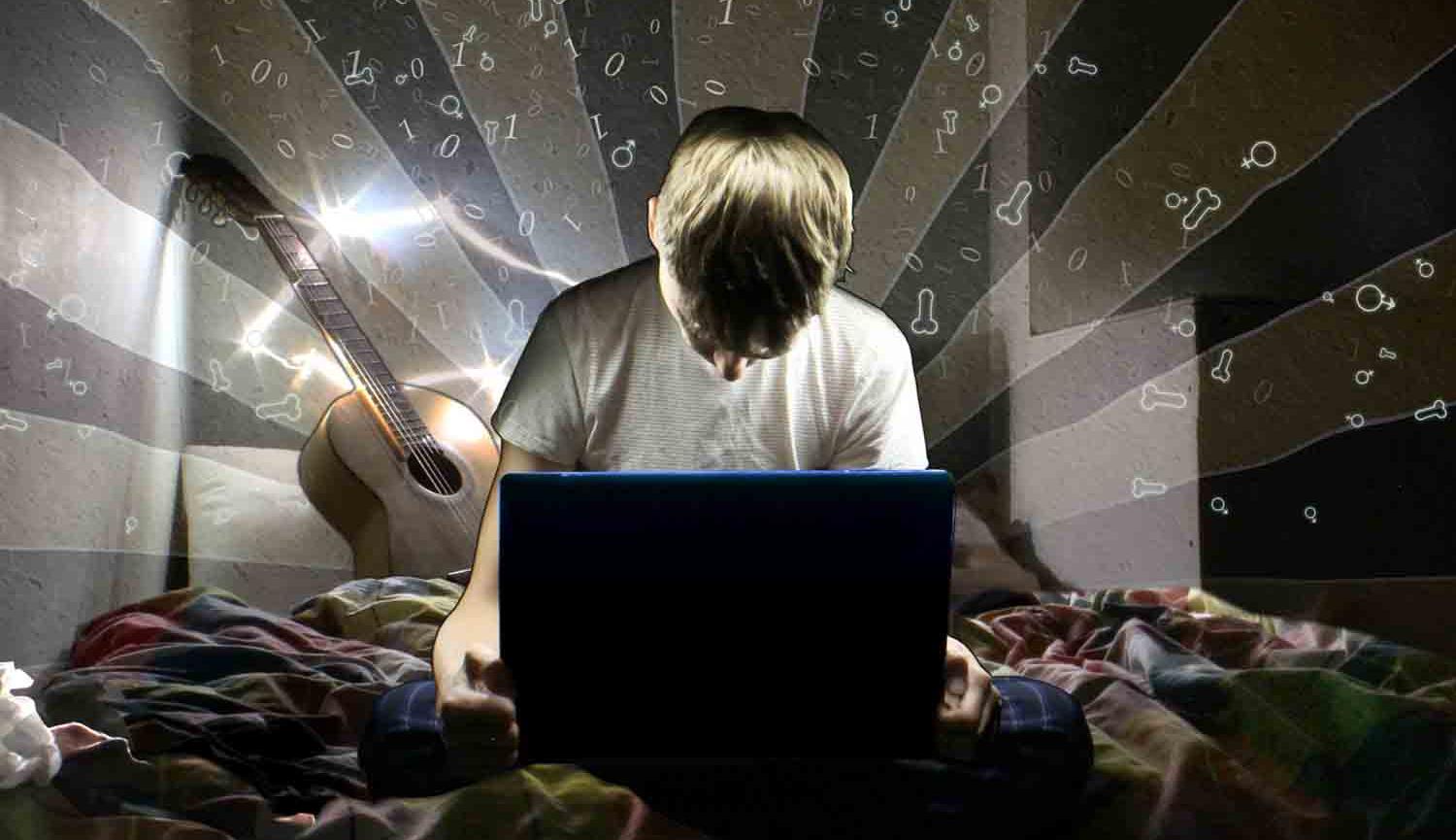 Photo of boy sitting on bed looking at laptop with guitar behind him
