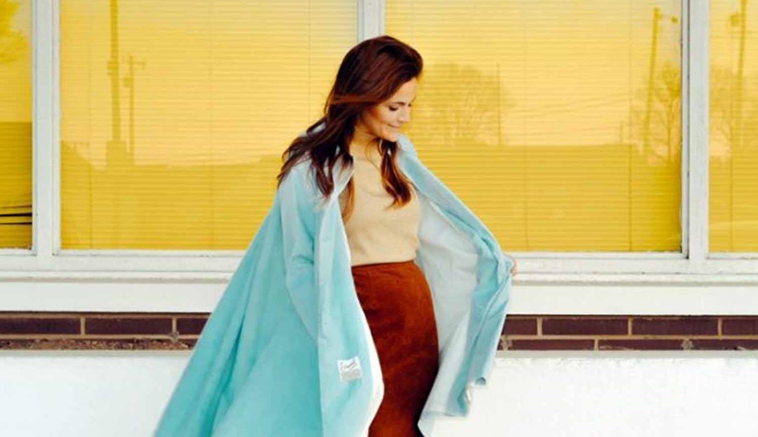 Photo of woman in front of window wearing cape