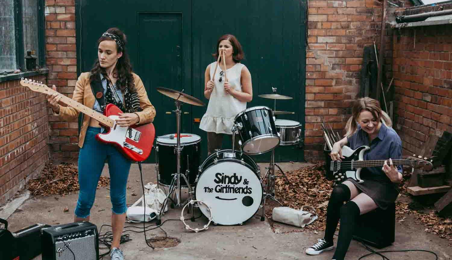 It'S Different For Girls image of three girls playing instruments in back yard