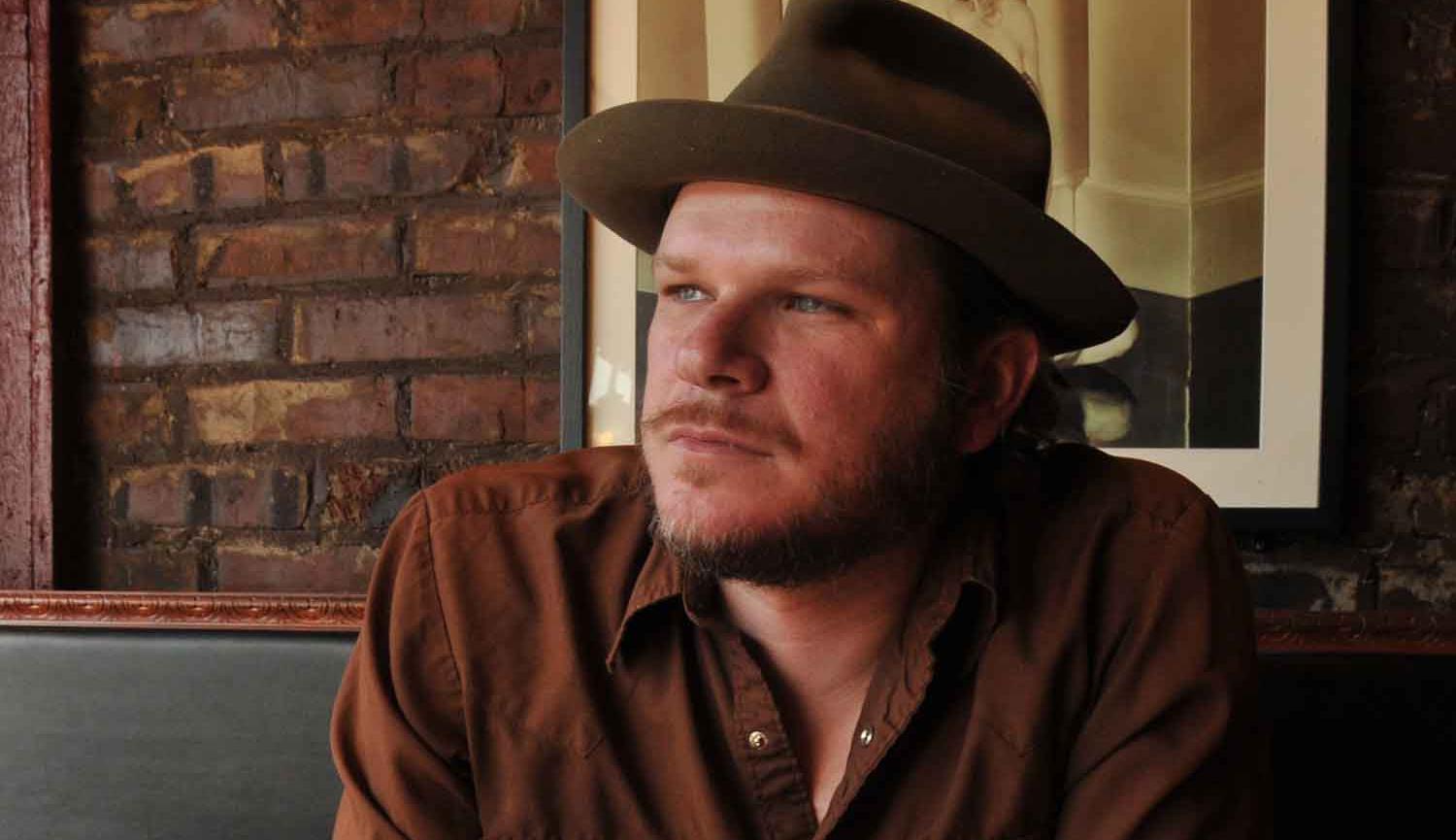 Image of Jason Eady sitting at table wearing hat