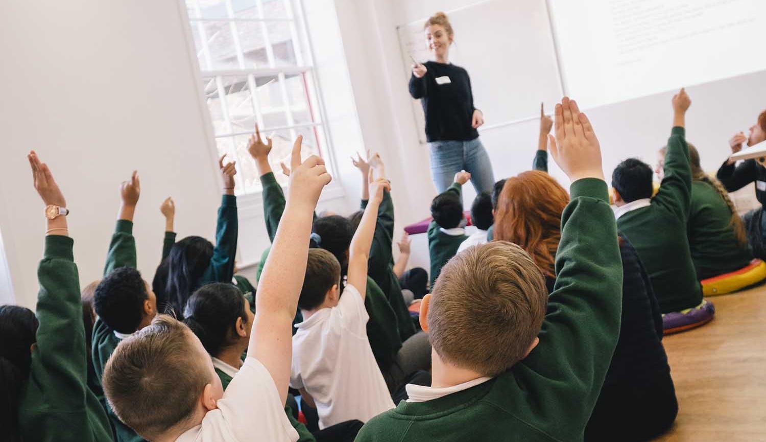 Group of children sitting on floor with hands up