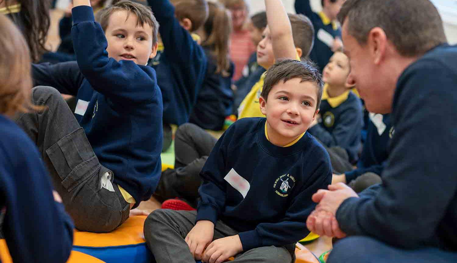 Group of children sitting on floor talking to an adult