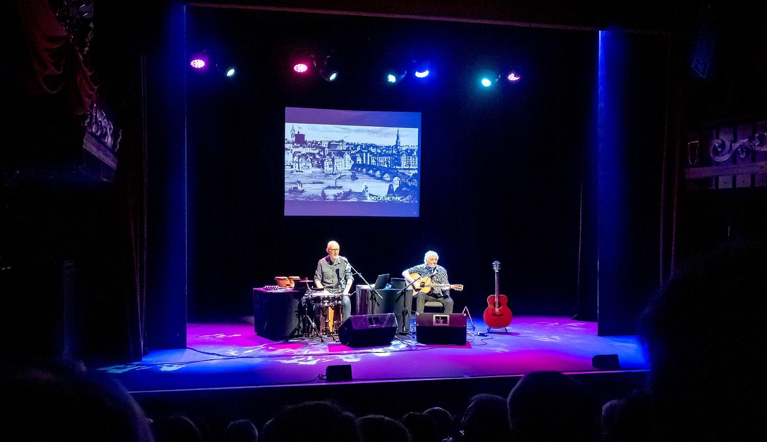 Photo of stage with two men playing musical instruments