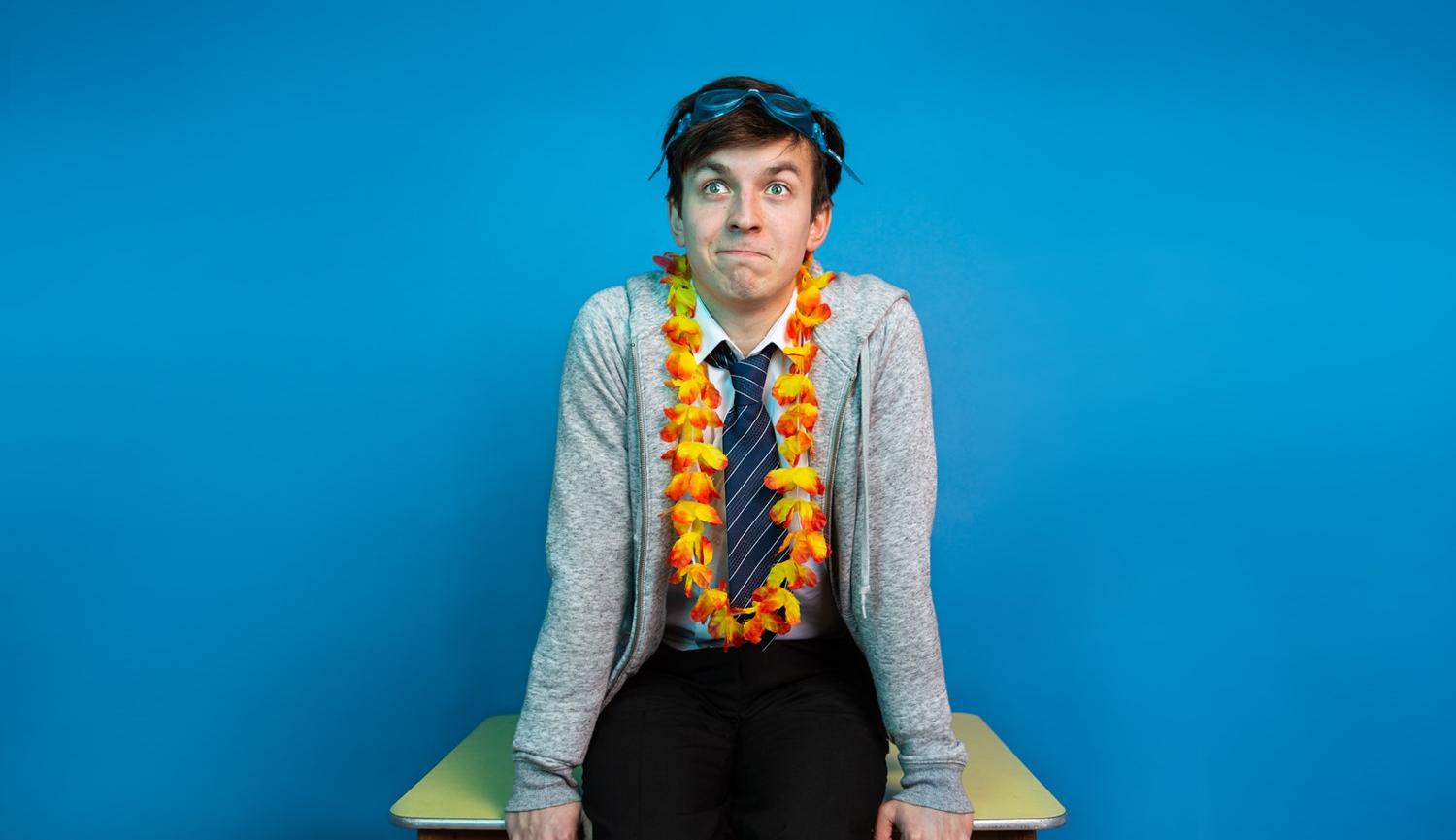 Photo of boy sitting on table wearing shirt & tie with swimming goggles on head