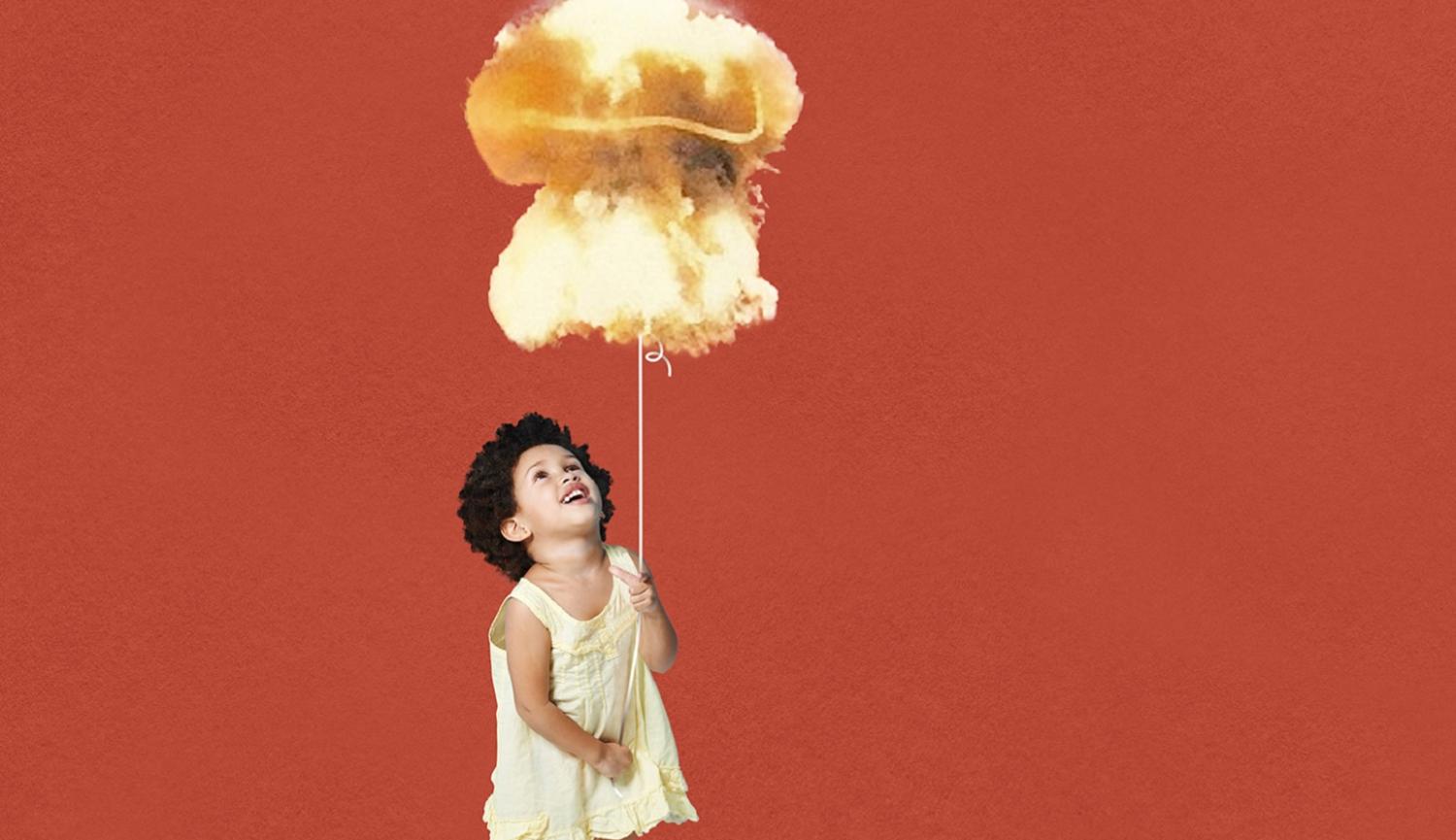 Small girl in dress holding string of a balloon in the shape of a nuclear mushroom cloud