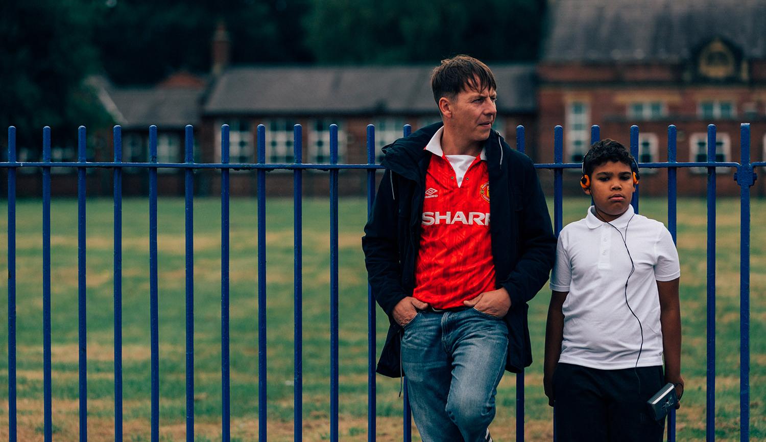 Man and boy next to fence