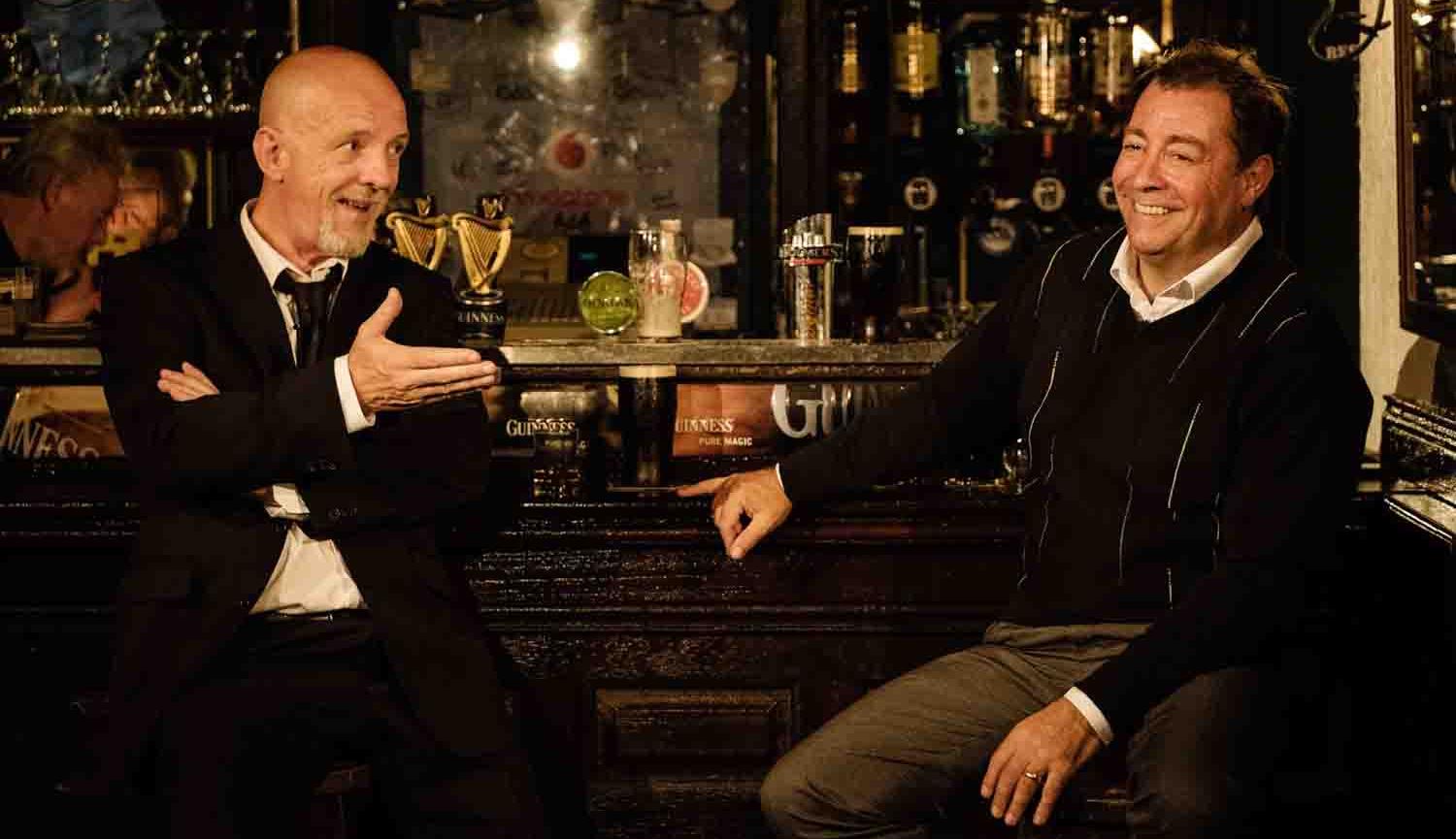 Two pints image of two men sitting at a bar talking