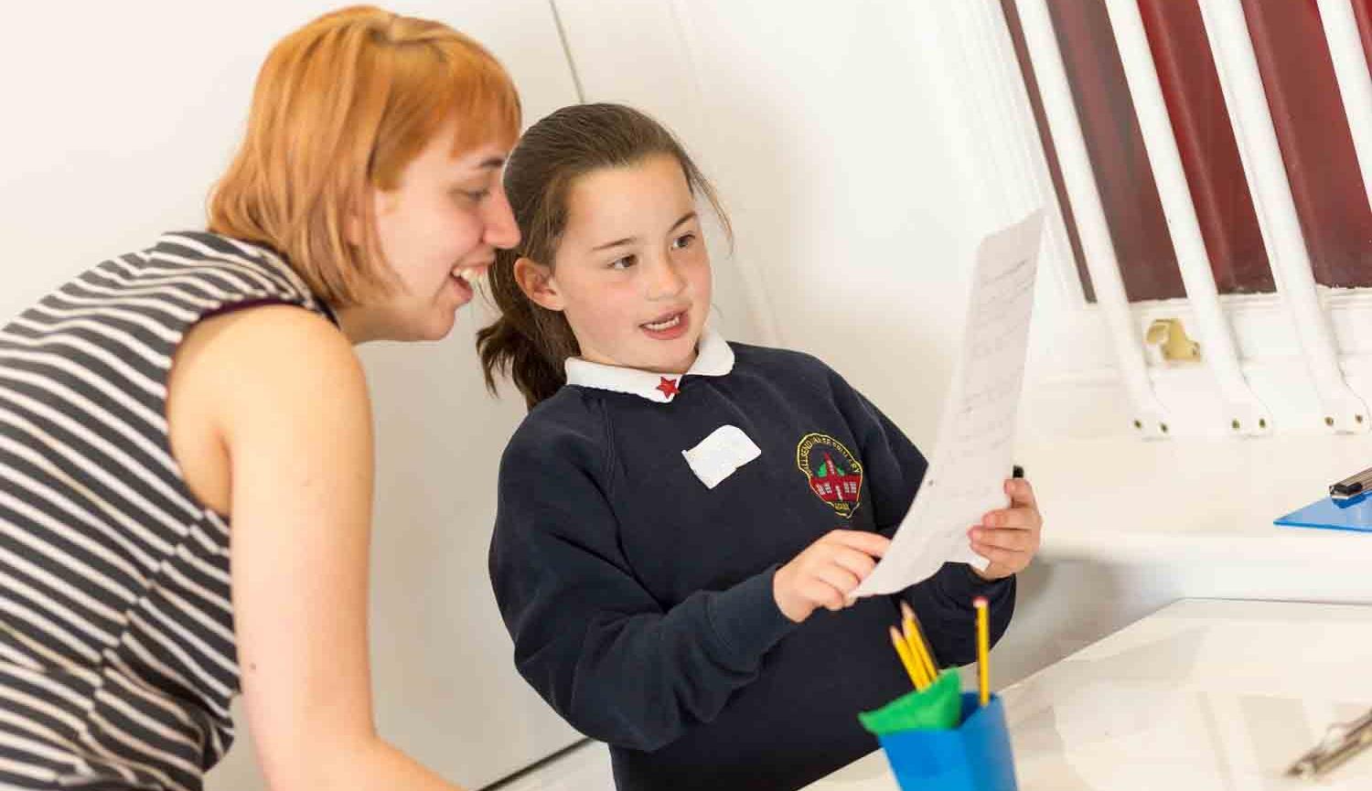 Woman helping child with writing