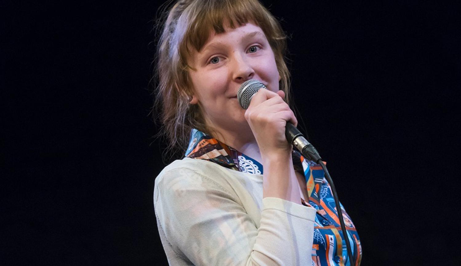 A young woman speaks into a microphone