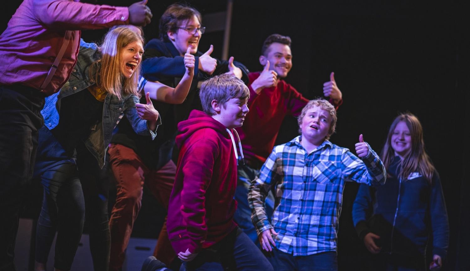 Photo of actors on stage giving thumbs up