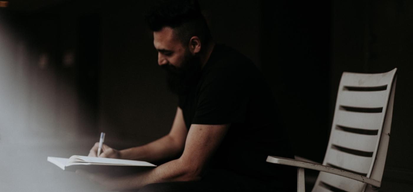 Man sitting on chair writing in book