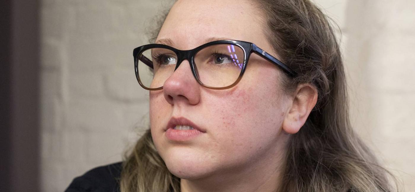 A young lady with fair hair and glasses looking into the distance - Bex Bowsher