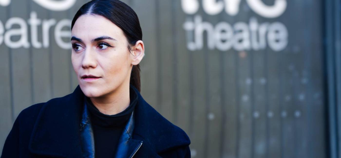 Nadine Shah standing in front of the Live Theatre doors looking off to her right