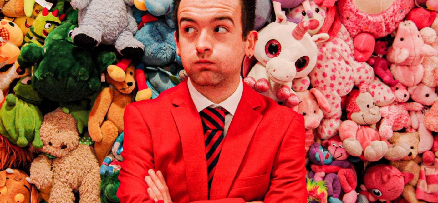 Lewis Jobson wearing a Butlin's Redcoat standing in front of a pile of cuddly toys