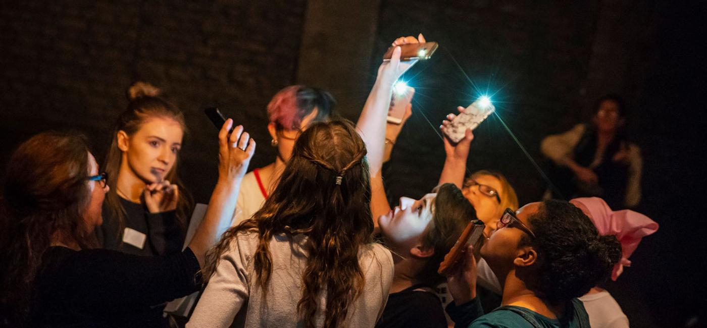 Young Women in a circle holding up phones