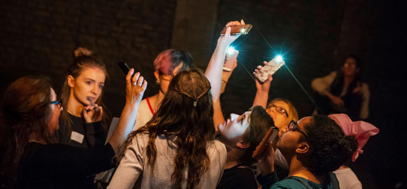 Young Women in a circle holding up phones