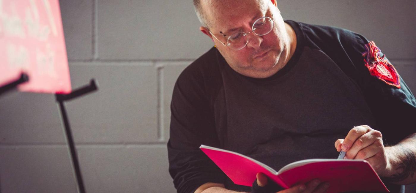 a man sitting writing in a red book