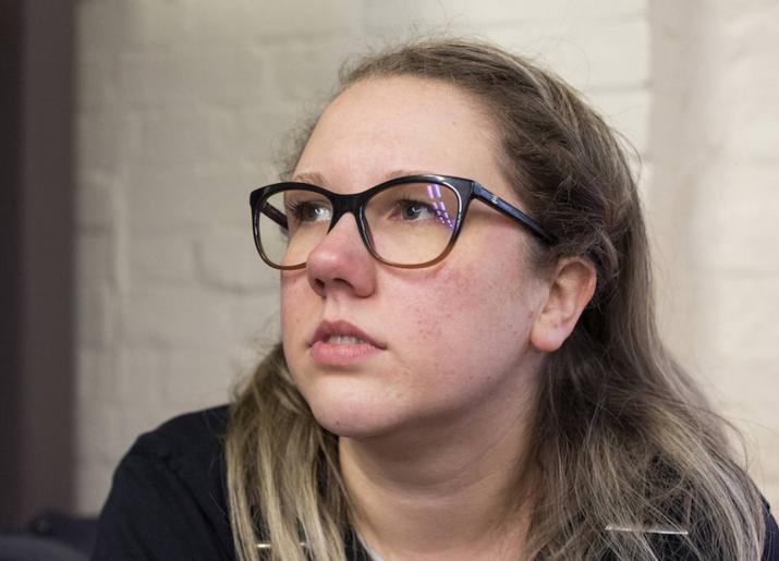 A young lady with fair hair and glasses looking into the distance - Bex Bowsher