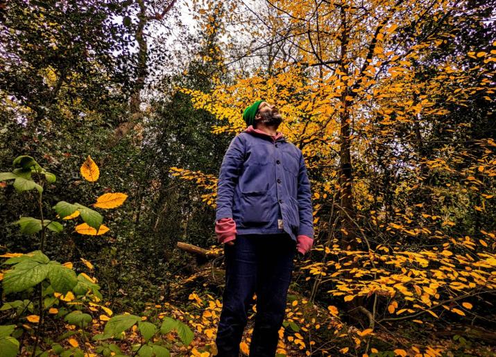 Daniel Kitson in a wood looking to the sky