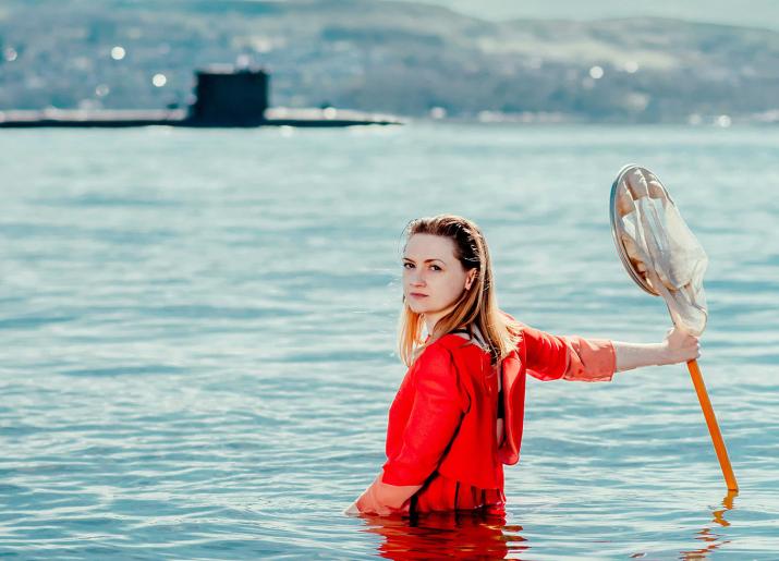 Woman in water in front of submarine 
