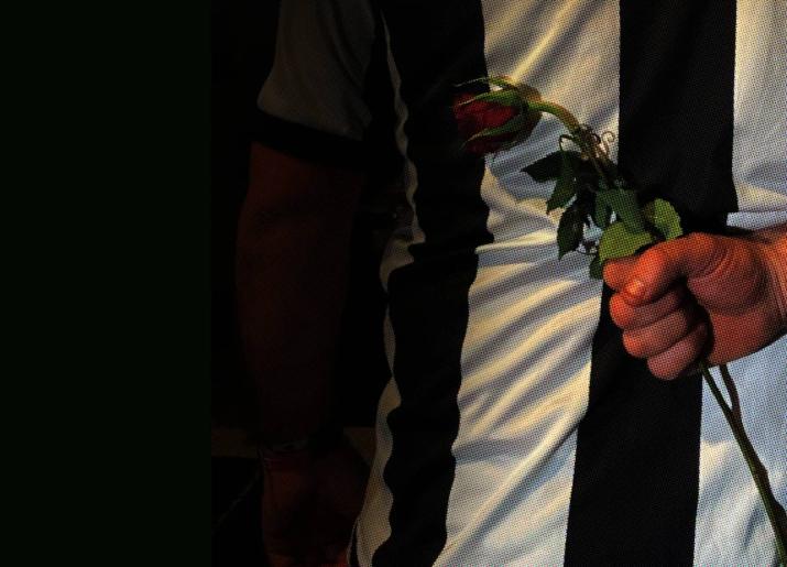 Man holding a rose behind his back - he is wearing a NUFC shirt