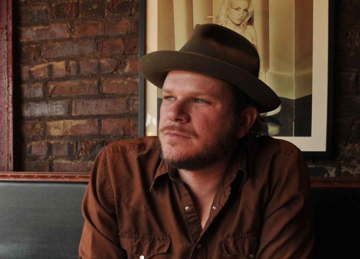 Image of Jason Eady sitting at table wearing hat