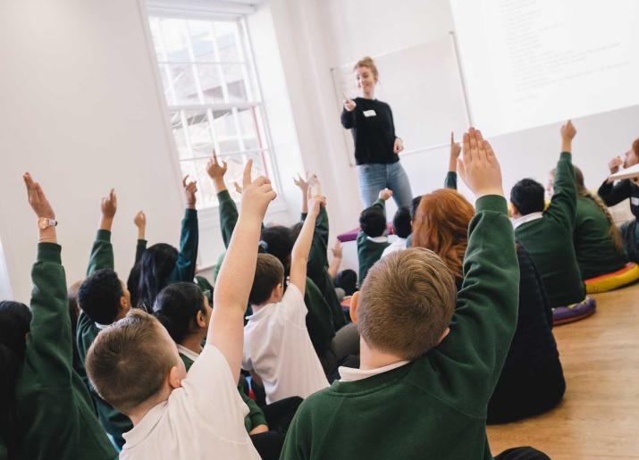 Group of children sitting on floor with hands up