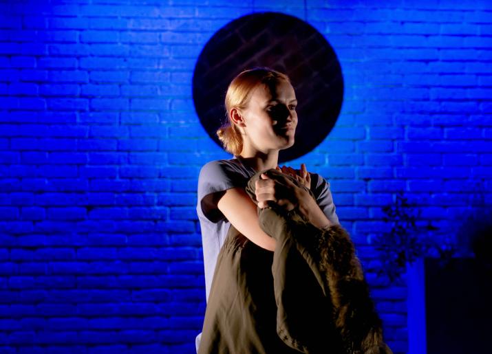 Photograph of a person standing arms crossed in front of a wall with a blue light 