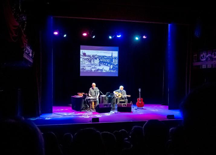 Photo of stage with two men playing musical instruments