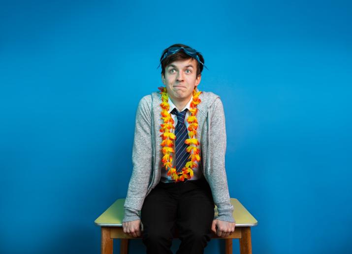 Photo of boy sitting on table wearing shirt & tie with swimming goggles on head