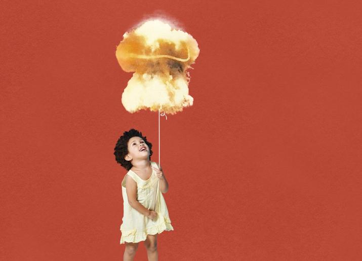 Small girl in dress holding string of a balloon in the shape of a nuclear mushroom cloud