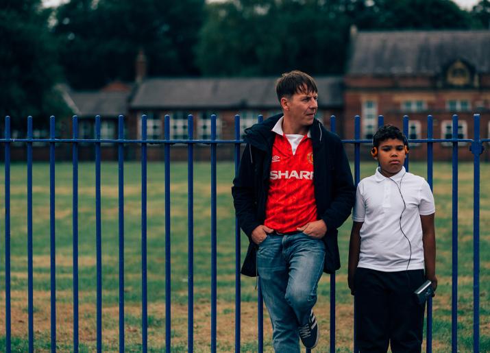 Man and boy next to fence