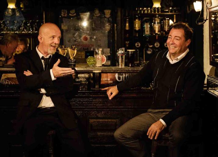 Two pints image of two men sitting at a bar talking