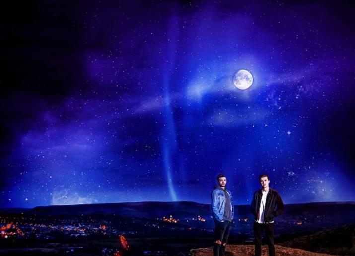 2 men standing underneath the moon - Under Three Moons