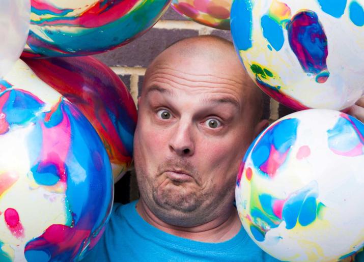 Jesterval Lee Kyle Family Show image of mans face surrounded by beach balls