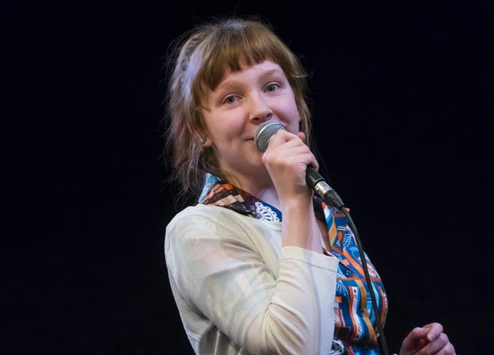 A young woman speaks into a microphone
