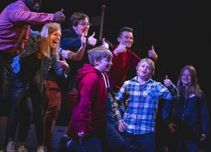 Photo of actors on stage giving thumbs up