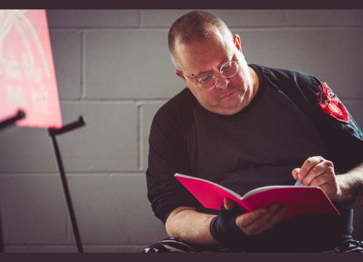 a man sitting writing in a red book