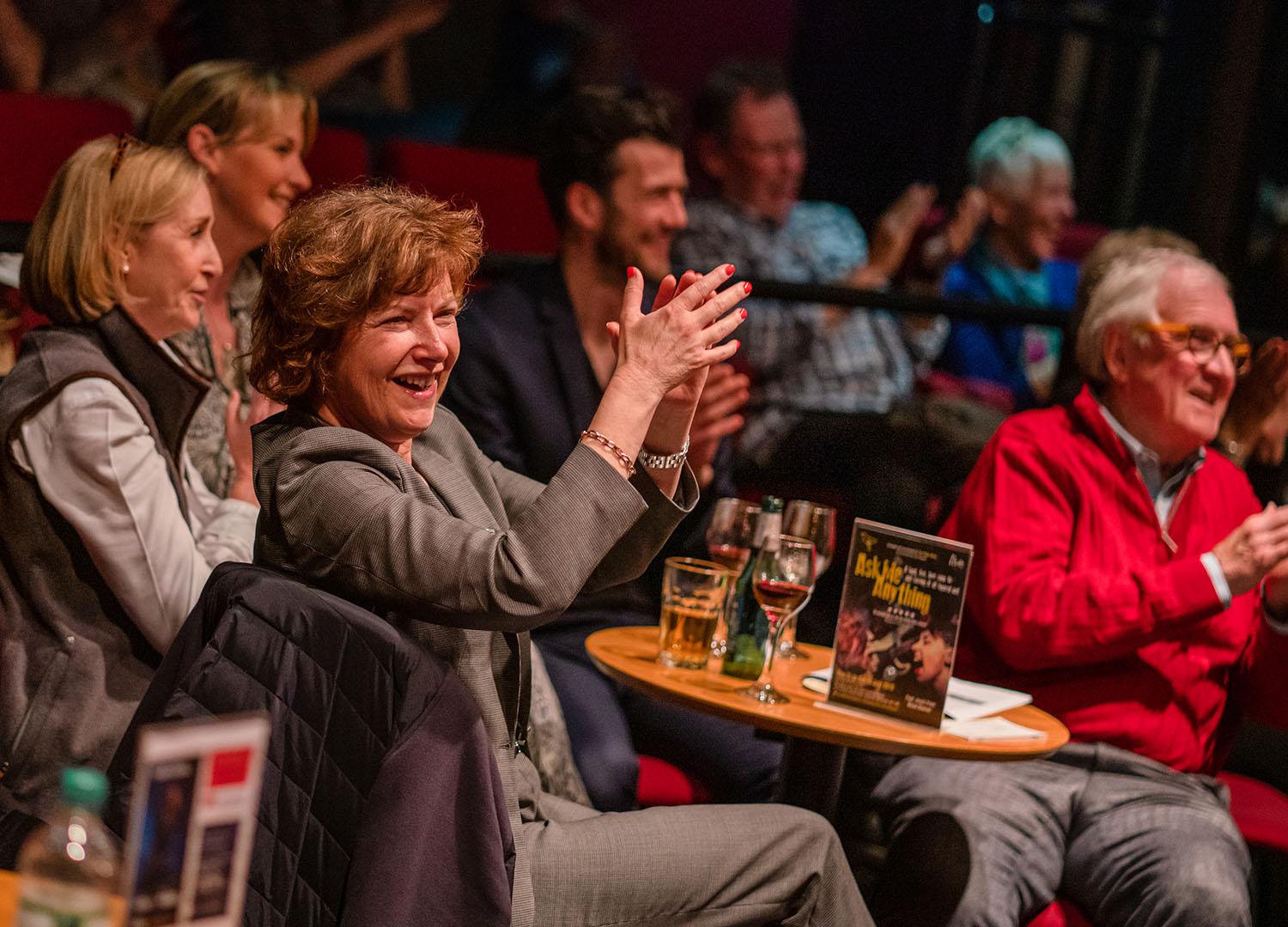 Group of people sitting at table applauding 